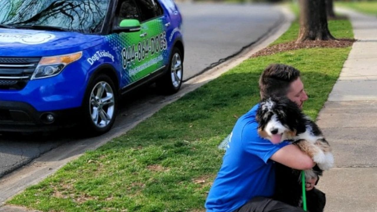 Photo of Dog Owner's Academy dog trainer hugging a client's dog outside in Charlotte, NC